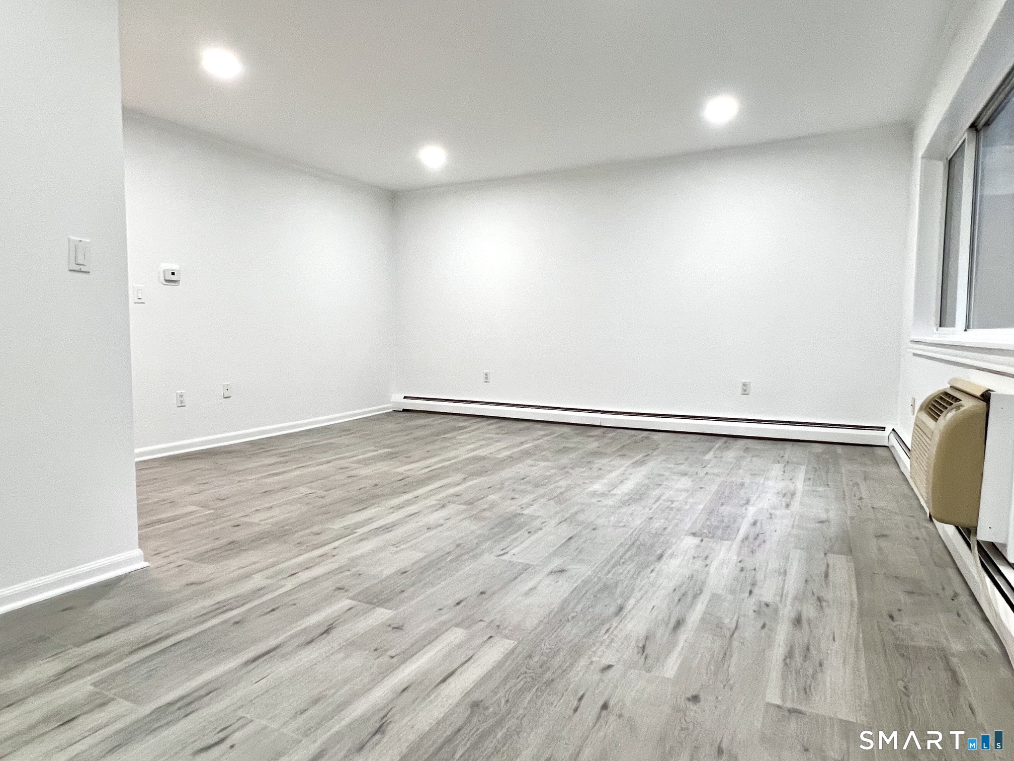 208 Flax Hill Road, Unit 32 Norwalk, CT 06854 - Photo 8 of 12 an empty room with wooden floor and windows