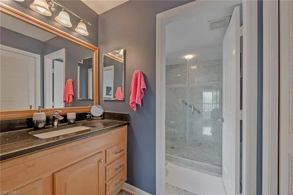 a bathroom with a granite countertop sink a mirror and a shower