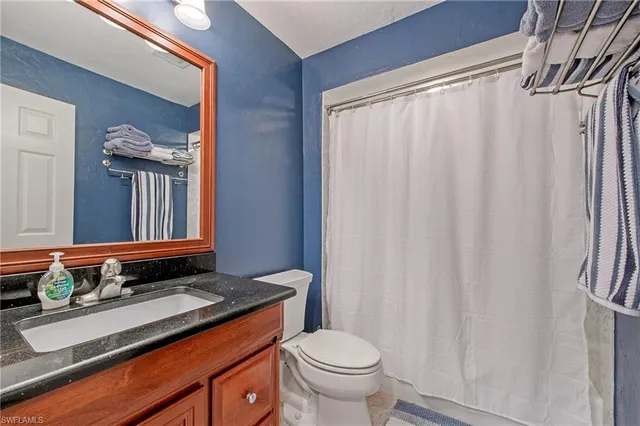 a bathroom with a granite countertop sink and a toilet