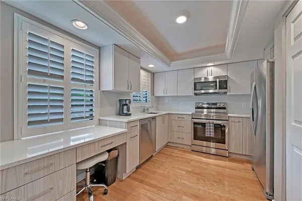 a kitchen with stainless steel appliances a sink cabinets and a window