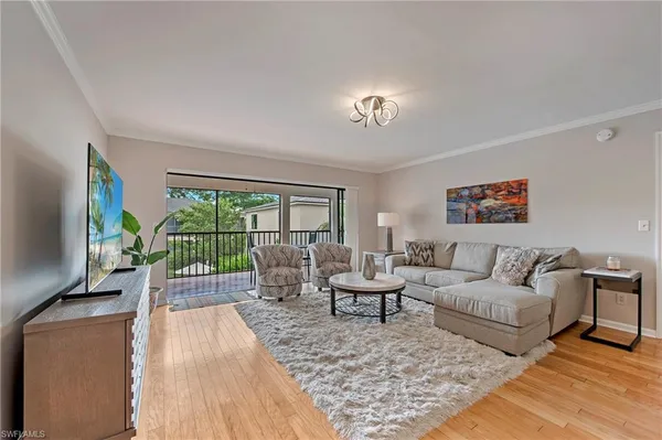 a living room with furniture floor to ceiling window and a flat screen tv