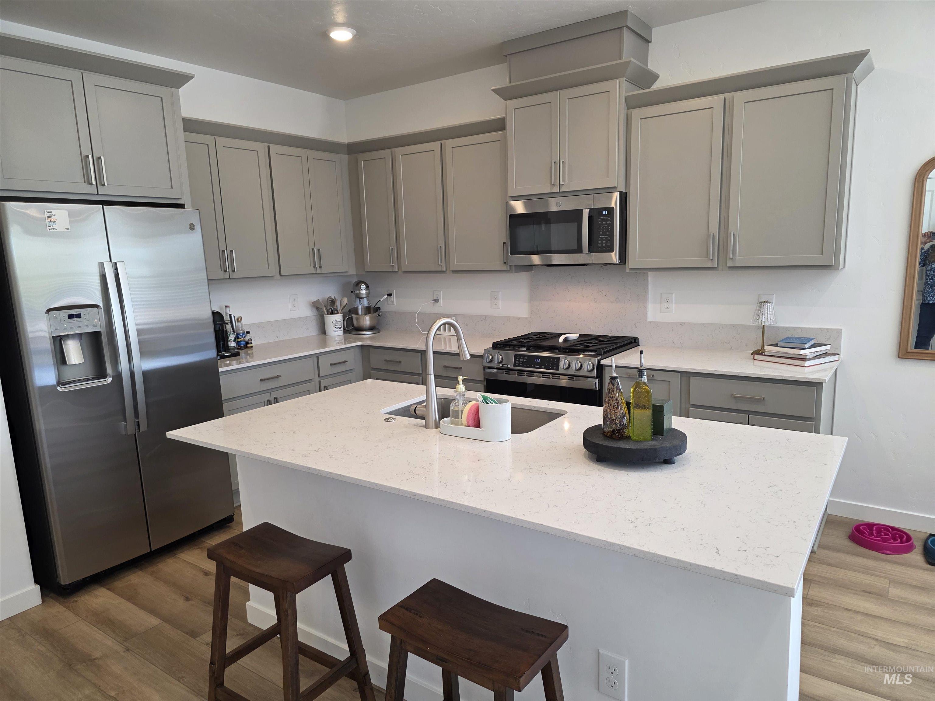 168 North Stratus Way Eagle, ID 83616 - Photo 17 of 35 Kitchen with stainless steel appliances, gray cabinetry, a kitchen island with sink, light stone countertops, and recessed lighting