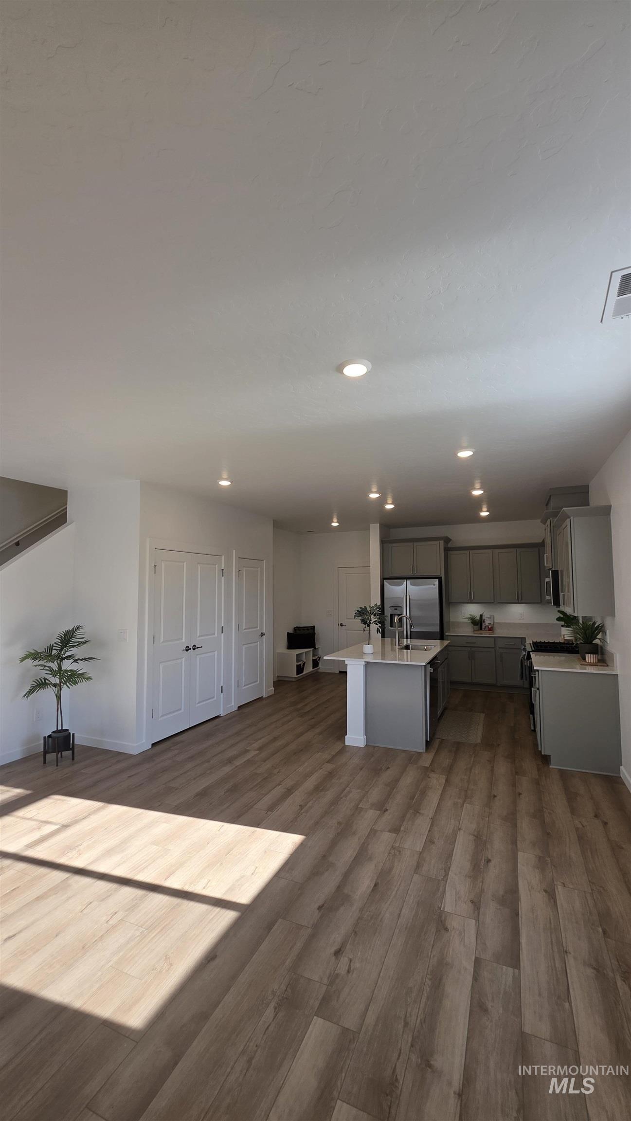 168 North Stratus Way Eagle, ID 83616 - Photo 34 of 35 Kitchen featuring open floor plan, light wood-style flooring, gray cabinetry, stainless steel fridge, and recessed lighting