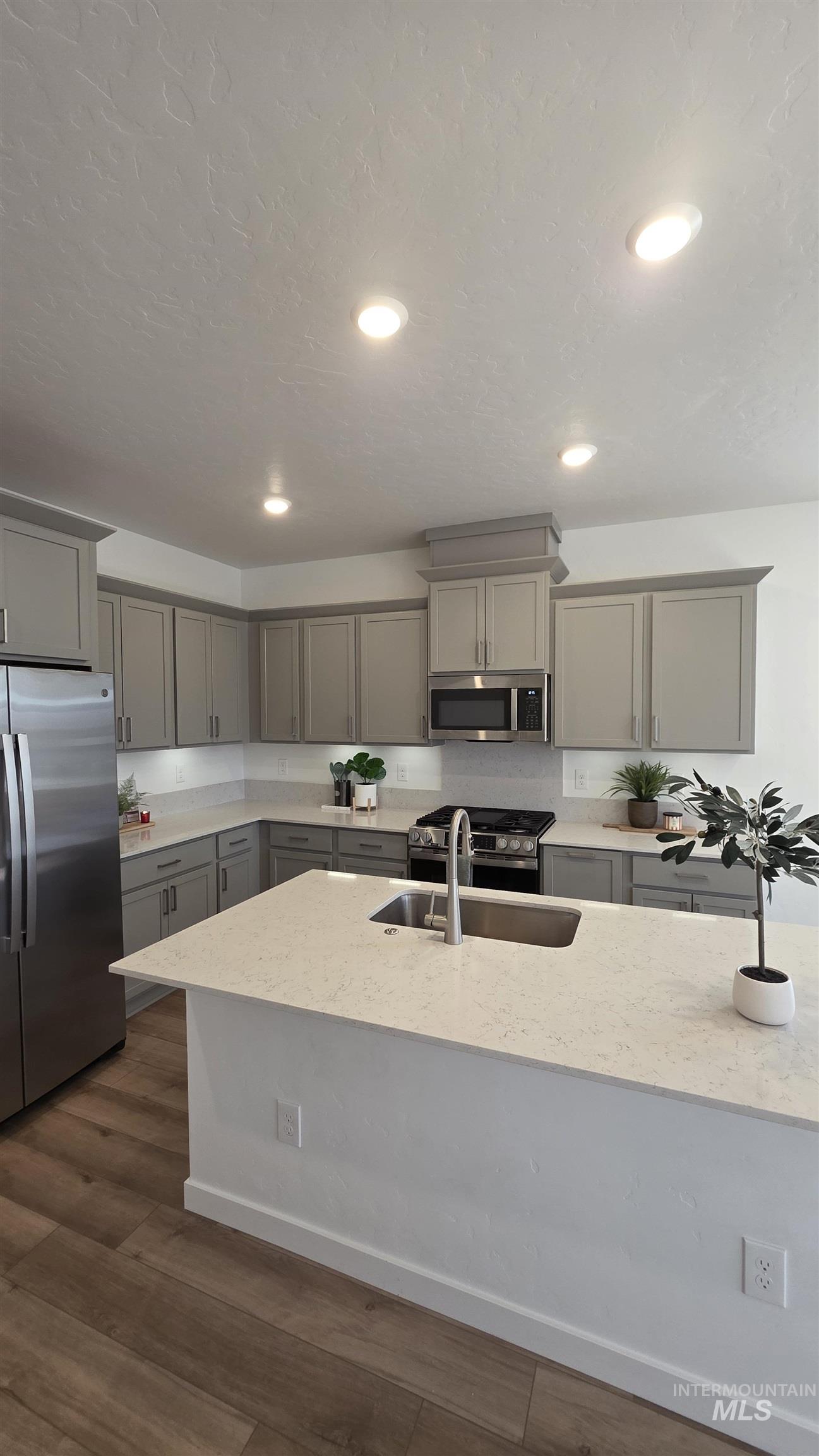168 North Stratus Way Eagle, ID 83616 - Photo 6 of 35 Kitchen with gray cabinets, stainless steel appliances, light stone countertops, dark wood-style flooring, and recessed lighting
