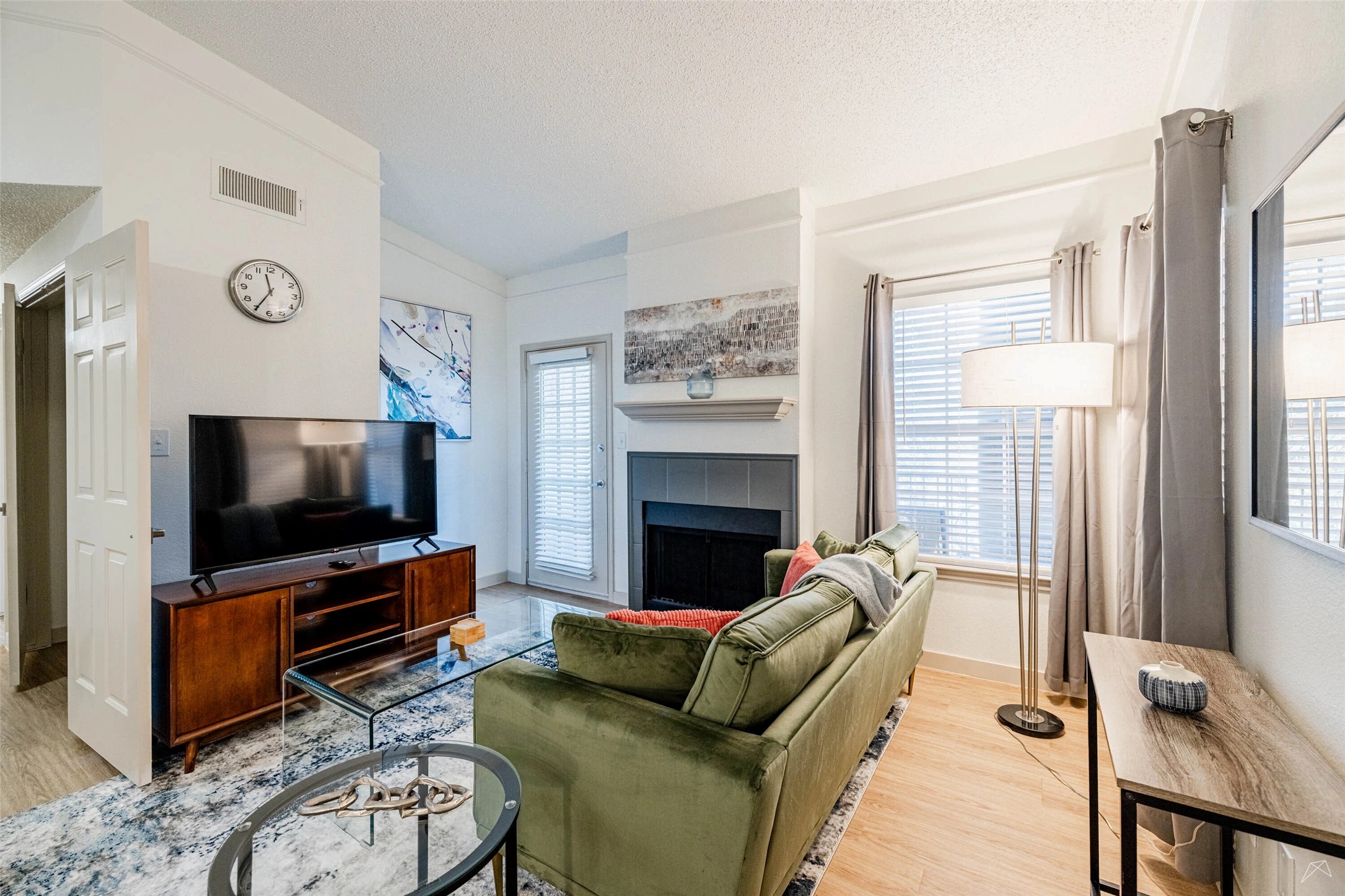 11908 Anderson Mill Road, Unit 822 Austin, TX 78726 - Photo 14 of 23 Living area featuring a tile fireplace, vaulted ceiling, light wood-style floors, and a textured ceiling