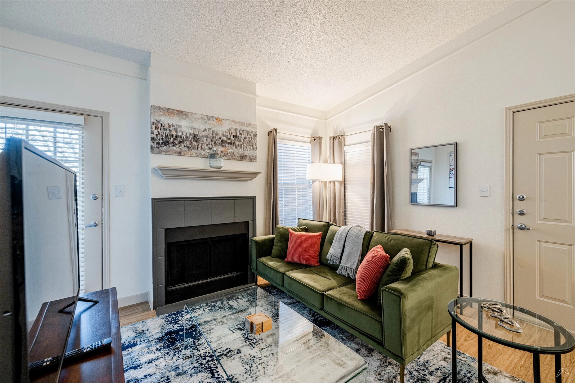 11908 Anderson Mill Road, Unit 822 Austin, TX 78726 - Photo 15 of 23 Living room with a textured ceiling, a tile fireplace, wood finished floors, lofted ceiling, and plenty of natural light