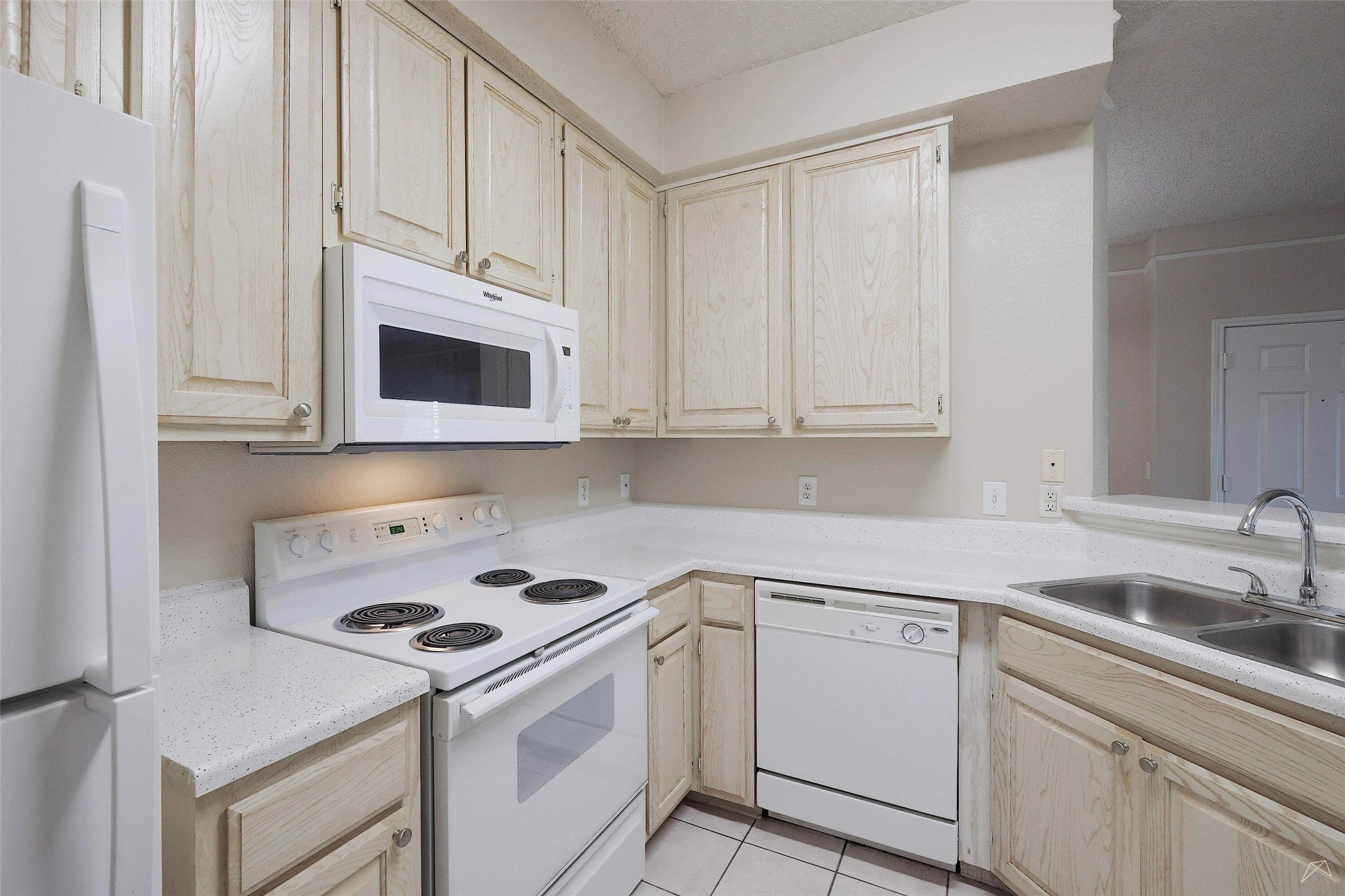 11908 Anderson Mill Road, Unit 822 Austin, TX 78726 - Photo 3 of 23 Kitchen featuring white appliances, light countertops, light brown cabinets, light tile patterned floors, and a textured ceiling