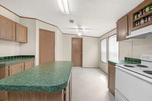 a kitchen with kitchen island granite countertop a stove a sink and a refrigerator