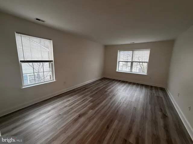 a view of an empty room with wooden floor and window