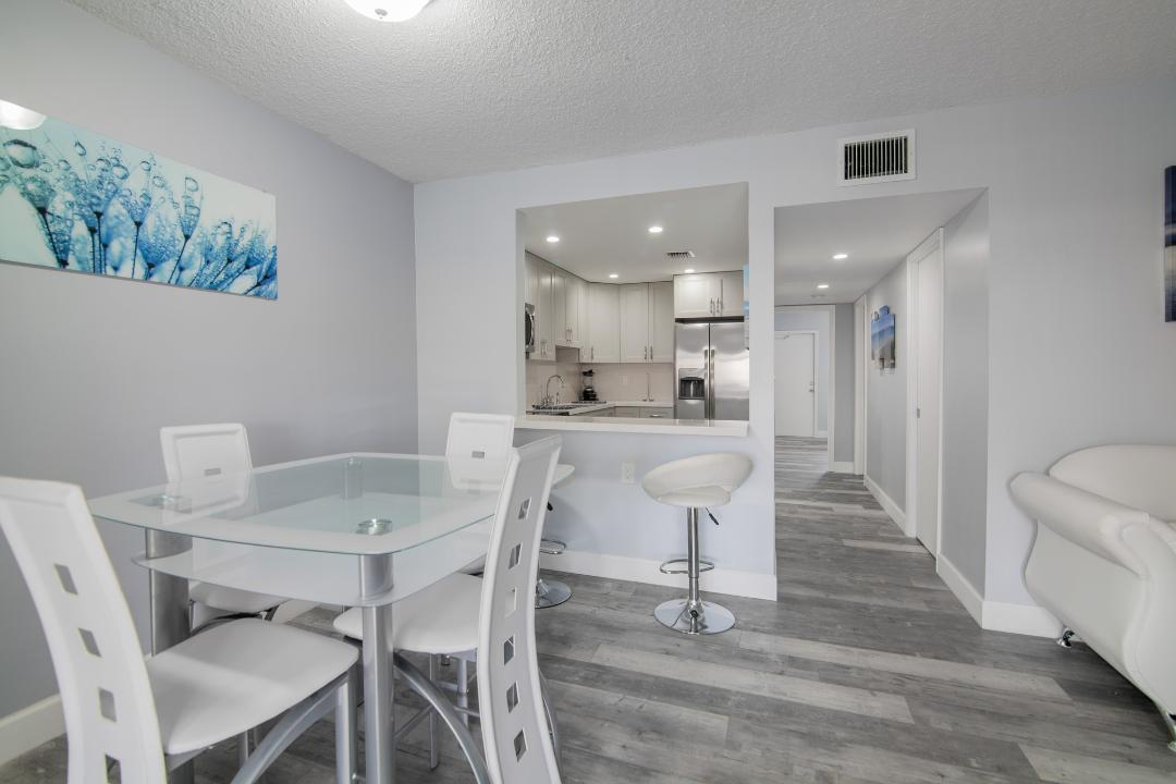 320 South Surf Road, Unit 205 Hollywood, FL 33019 - Photo 4 of 18 a dining area with a table chairs and a kitchen view