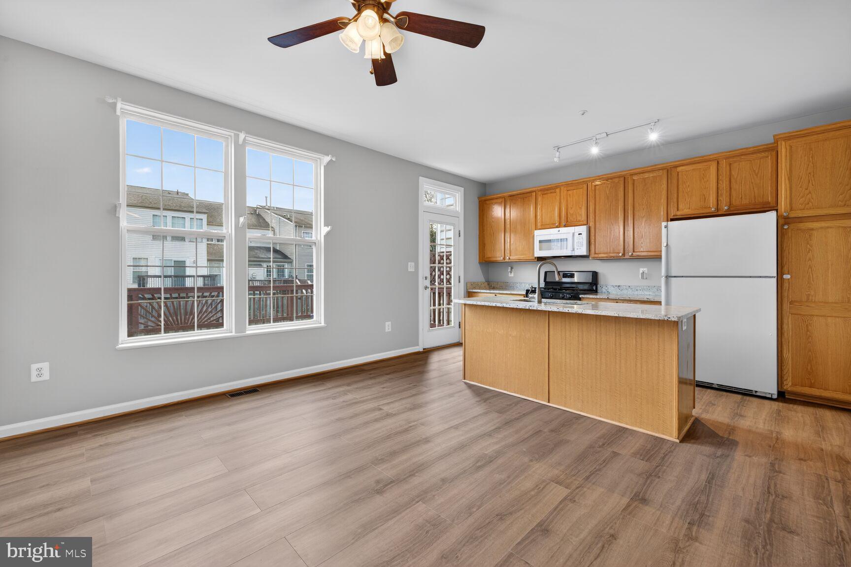 6715 Manorly Court Frederick, MD 21703 - Photo 2 of 15 a kitchen with stainless steel appliances wooden floors and white cabinets