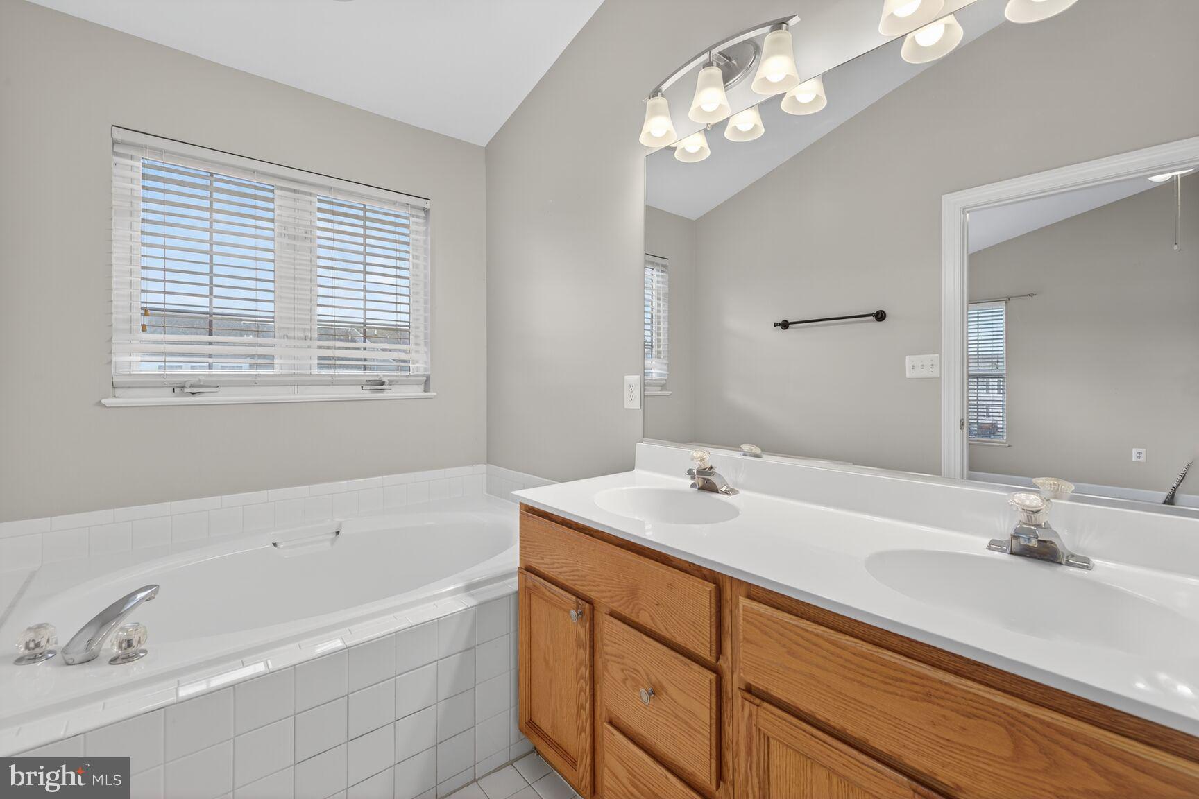 6715 Manorly Court Frederick, MD 21703 - Photo 9 of 15 a bathroom with a tub a sink and mirror