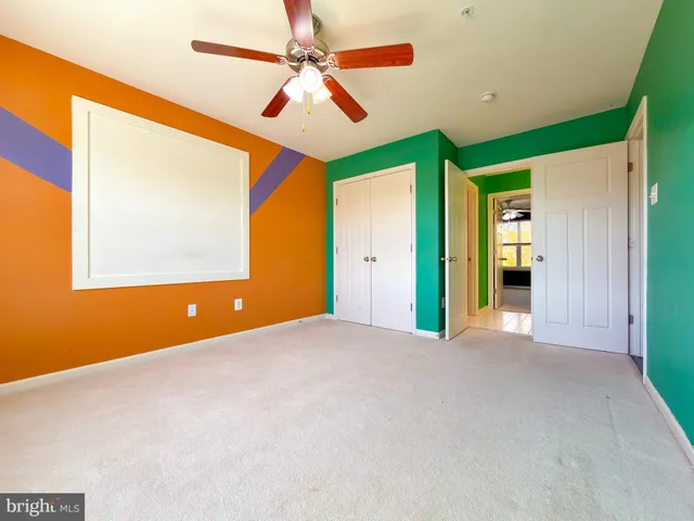an empty room with closet and ceiling fan