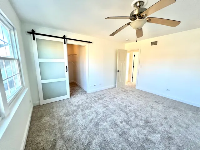 an empty room with windows and fan