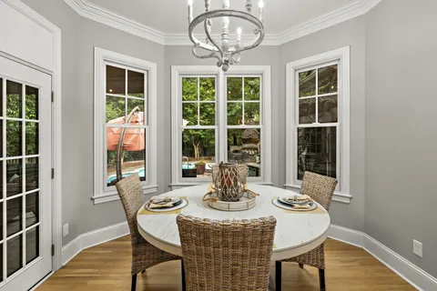 a dining room with furniture large windows and wooden floor