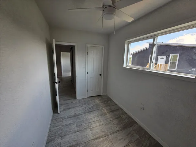an empty room with wooden floor closet and windows