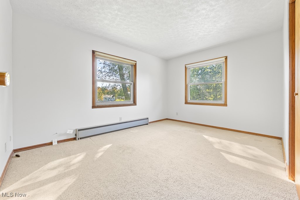 1165 Homeworth Road Alliance, OH 44601 - Photo 23 of 36 Unfurnished room with plenty of natural light, carpet, a textured ceiling, and baseboard heating