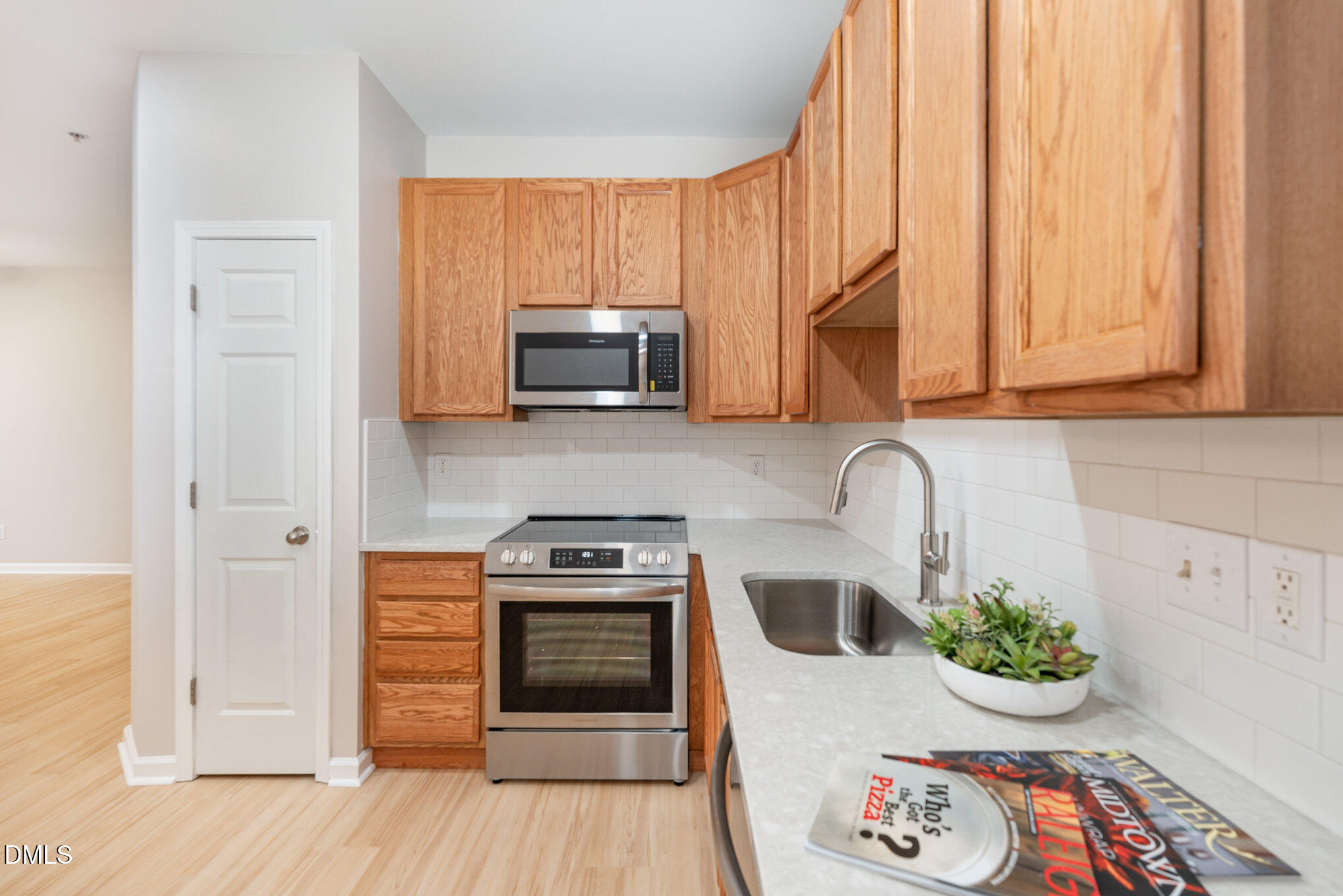 311 Gilman Lane, Unit 107 Raleigh, NC 27610 - Photo 6 of 21 a kitchen with stainless steel appliances a stove a microwave and wooden floor