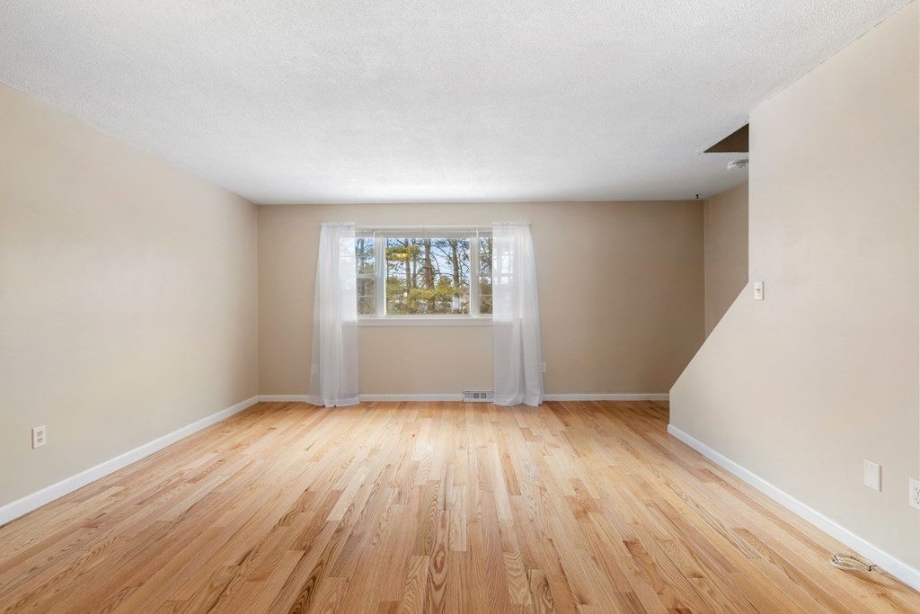 20 Hemlock Circle, Unit 20 Millis, MA 02054 - Photo 5 of 27 an empty room with wooden floor and windows