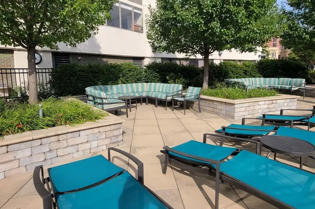 a view of a patio with couches table and chairs with potted plants and a small yard