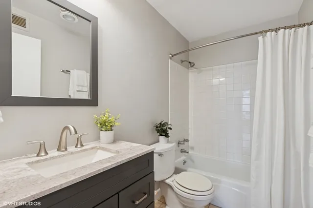 a bathroom with a granite countertop sink a toilet a mirror a vanity and shower