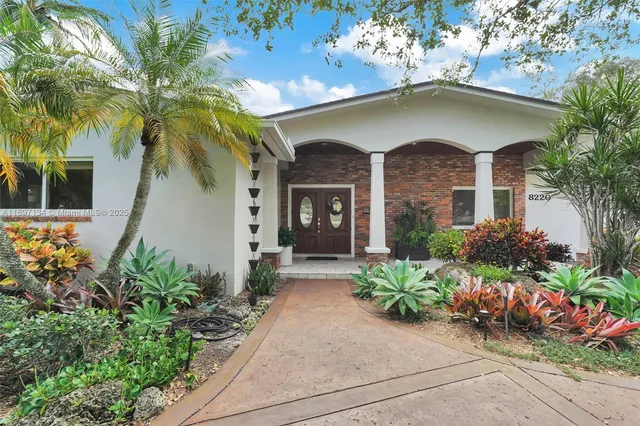 a front view of a house with a yard and potted plants