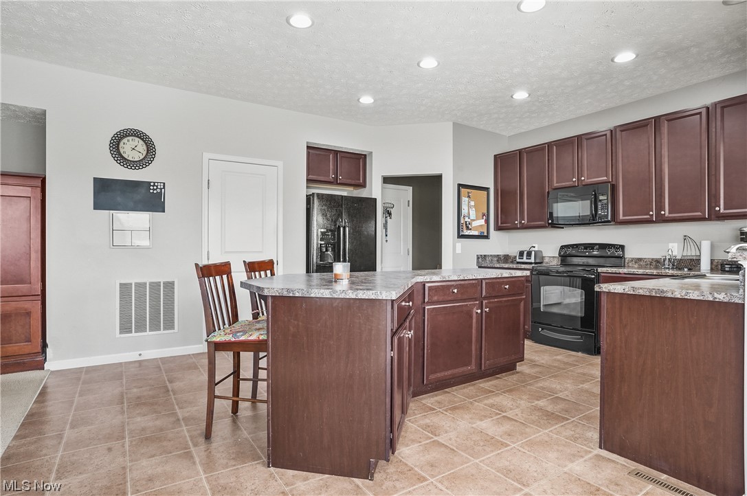 4169 Whitestone Road Kent, OH 44240 - Photo 12 of 33 Kitchen featuring light tile floors, black appliances, and a kitchen island