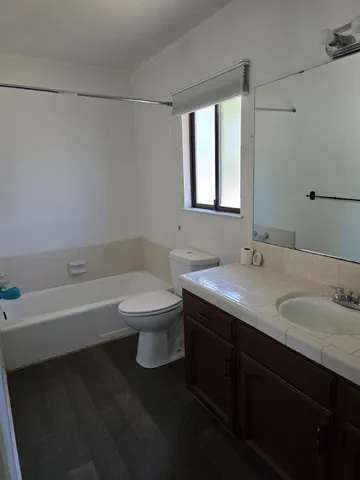 a bathroom with a granite countertop sink a toilet and bathtub
