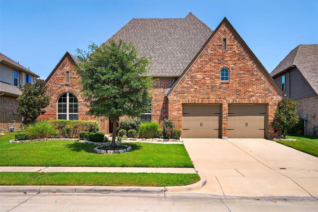 Tudor house with brick siding, concrete driveway, a front lawn, and roof with shingles