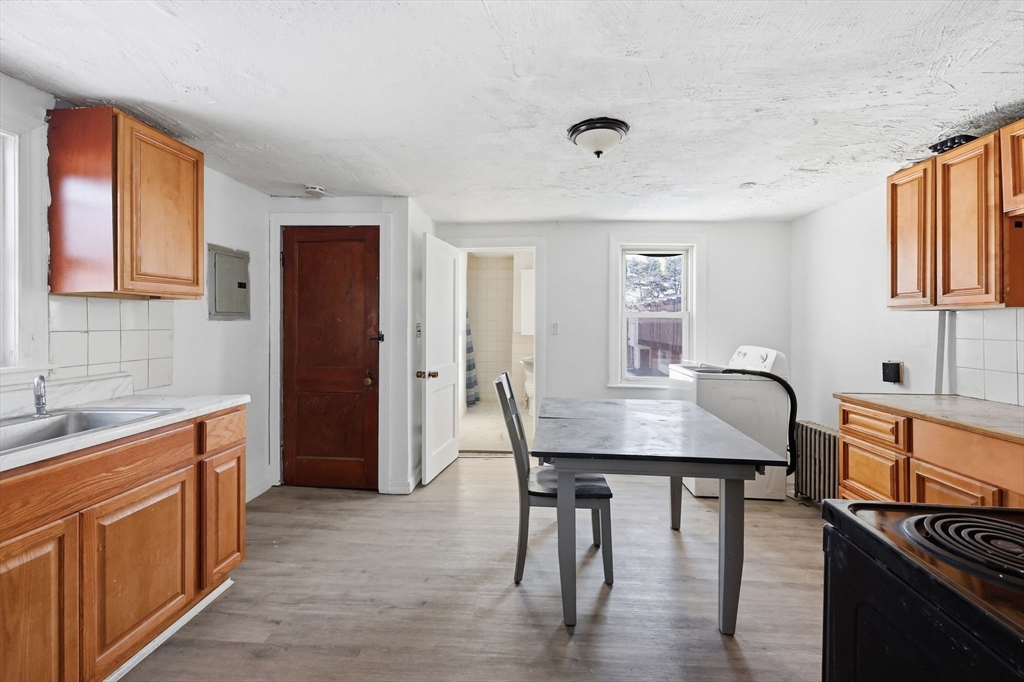 875 North Main Street Randolph, MA 02368 - Photo 25 of 42 a dining room with kitchen island stainless steel appliances granite countertop a sink a stove a dining table and chairs with wooden floor
