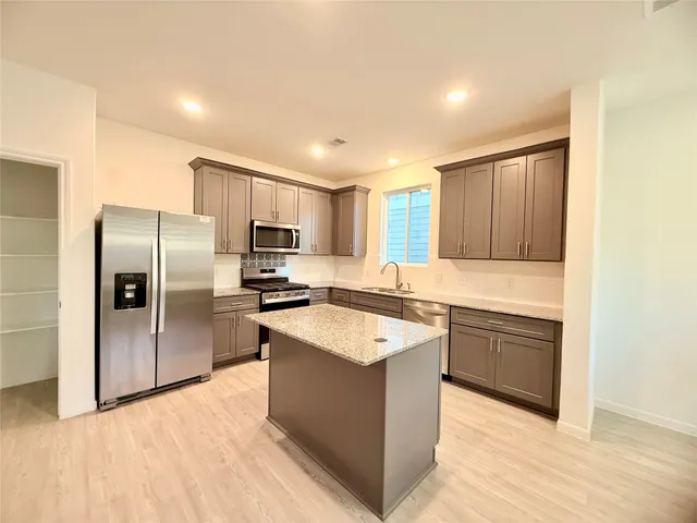 a kitchen with stainless steel appliances kitchen island granite countertop a sink counter and chairs