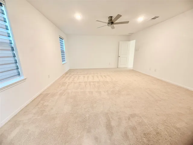 an empty room with windows and fan