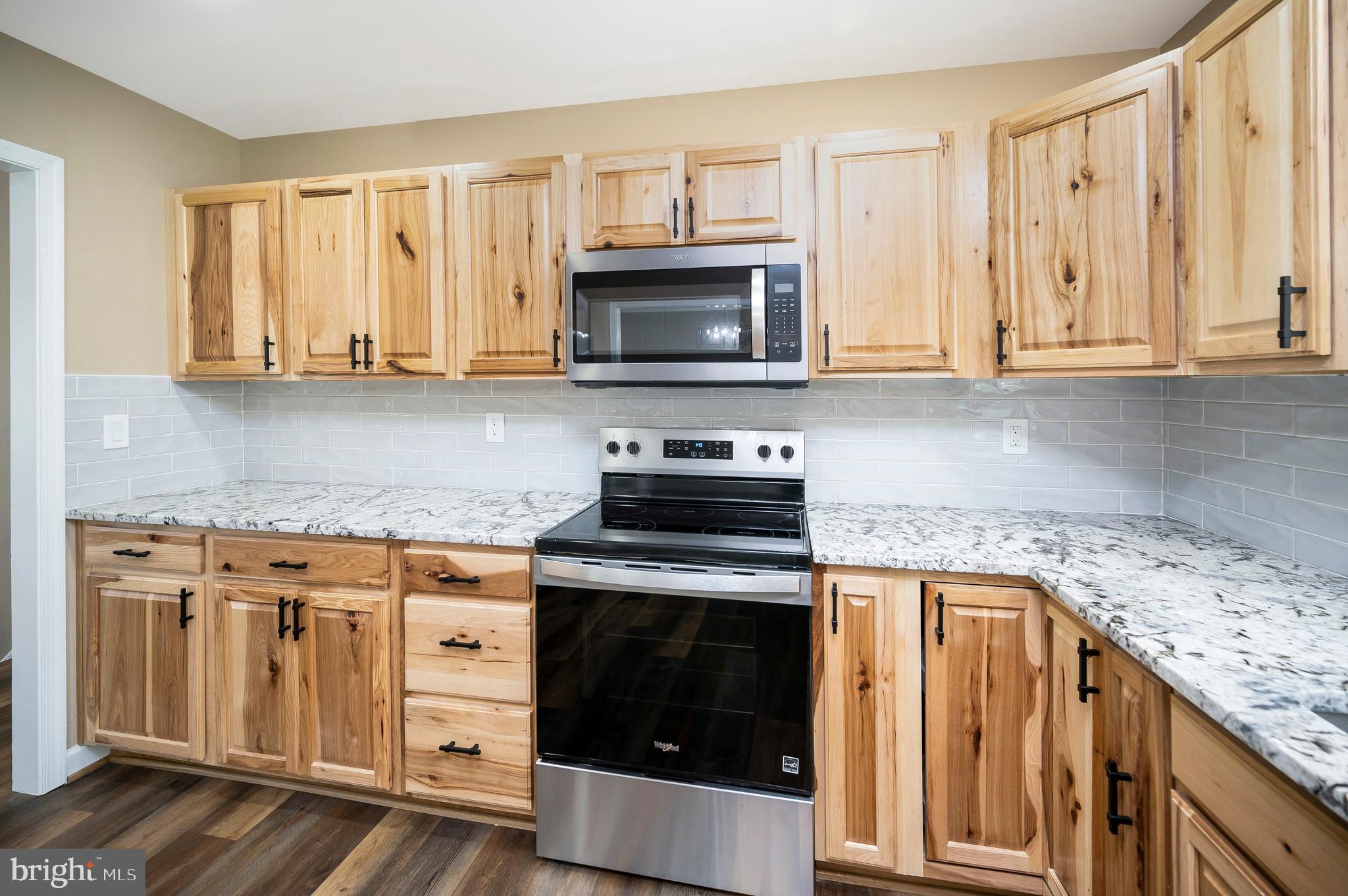13452 Post Oak Road Spotsylvania, VA 22551 - Photo 25 of 56 a kitchen with granite countertop a stove top oven microwave and cabinets