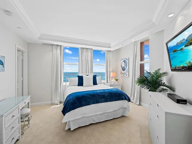 a spacious bedroom with a large bed and a flat tv screen on dresser
