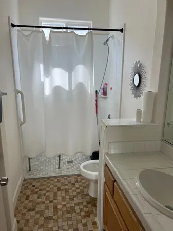 a bathroom with a granite countertop sink a toilet and shower
