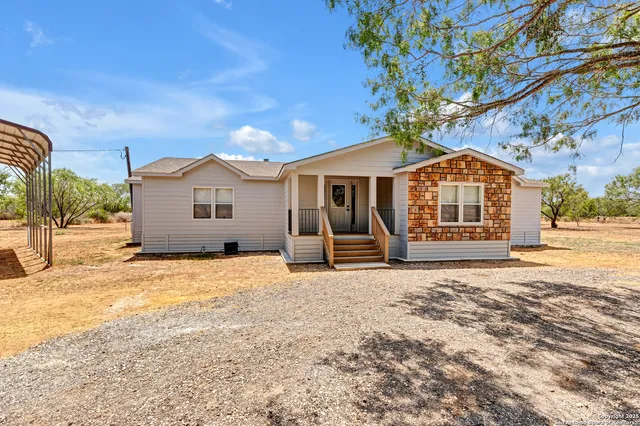 a view of a house with a yard and large tree