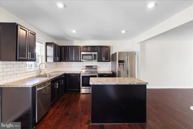 a kitchen with stainless steel appliances kitchen island granite countertop a stove a sink and a microwave