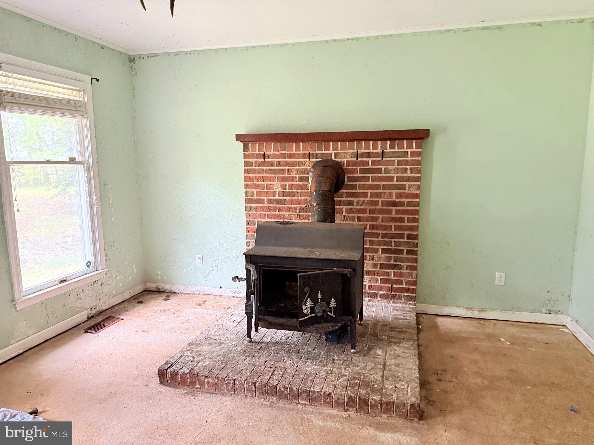 9532 Corkell Road Denton, MD 21629 - Photo 8 of 20 a view of an empty room with a fireplace and a window