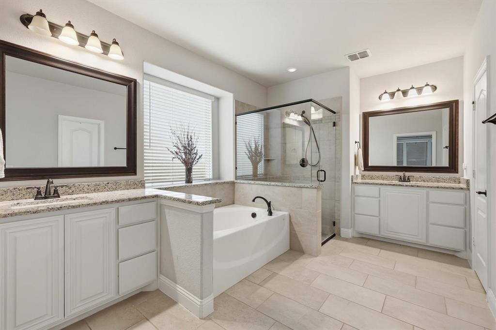 924 Timber Ridge Drive Justin, TX 76247 - Photo 20 of 32 Bright bathroom featuring dual vanity sinks with granite countertops, a built-in soaking tub, a separate glass-enclosed shower, and tile flooring
