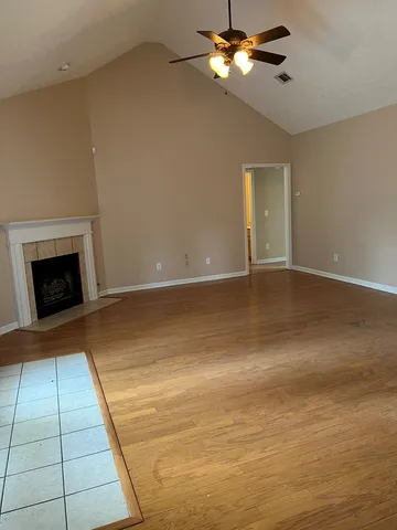a view of an empty room with chandelier fan and fire place