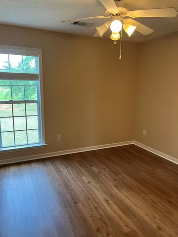 a view of an empty room with wooden floor and window