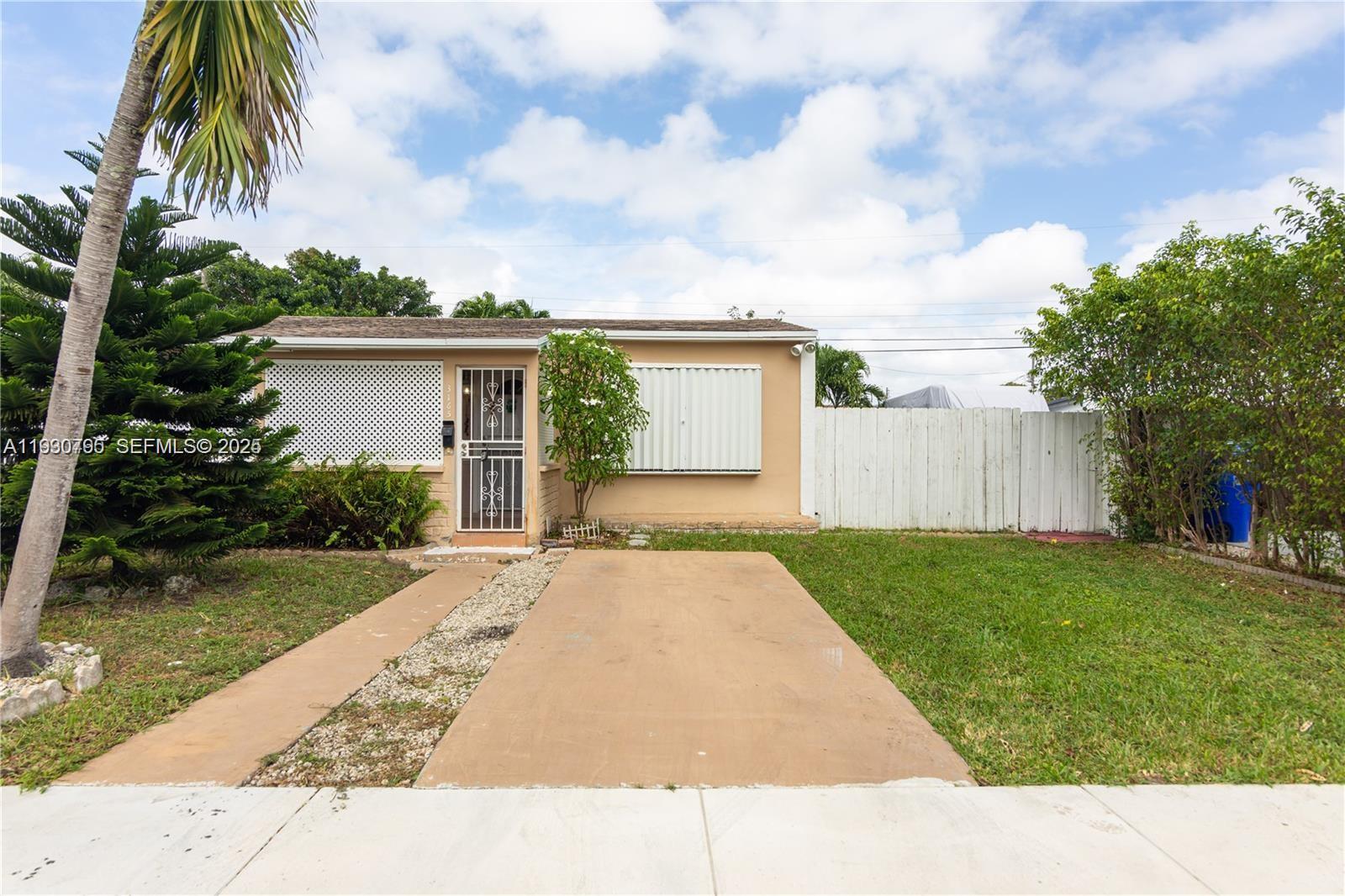front view of house with a yard and palm trees