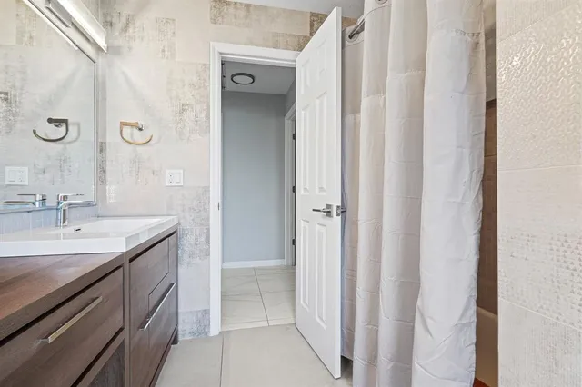 a spacious bathroom with a granite countertop sink a mirror and a shower