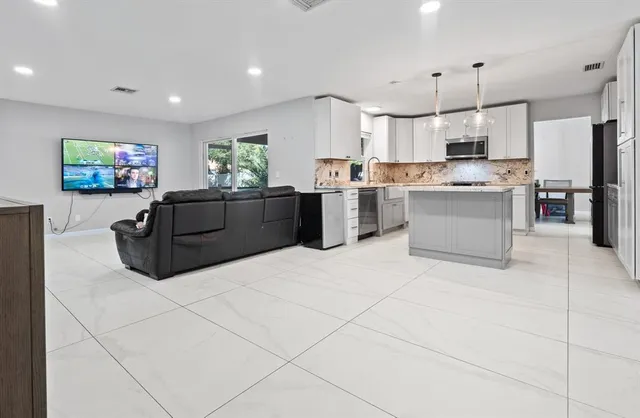 a kitchen with stainless steel appliances kitchen island granite countertop a refrigerator and a stove top oven