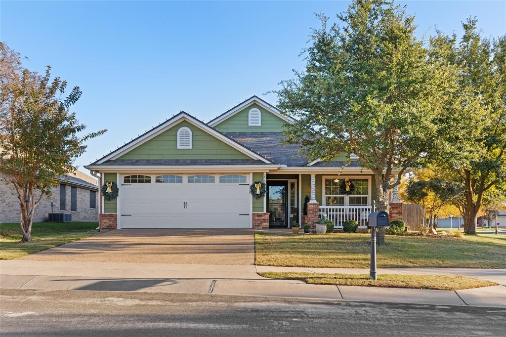 Craftsman-style house with a porch, concrete driveway, a front yard, and brick siding