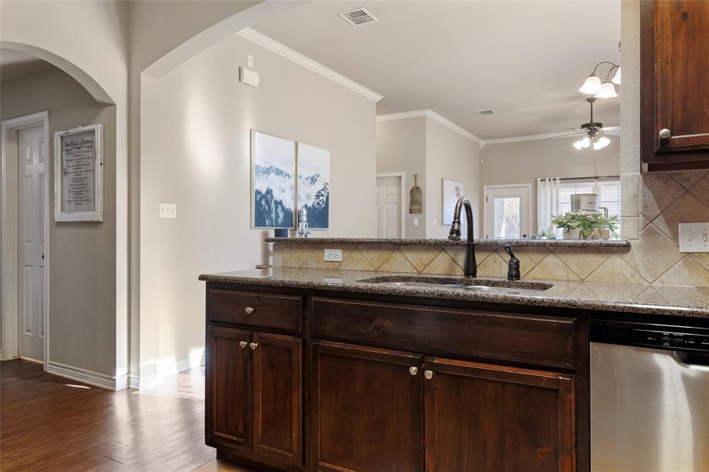 2565 Paddock Lane Robinson, TX 76706 - Photo 14 of 32 Kitchen featuring stainless steel dishwasher, dark brown cabinetry, decorative backsplash, dark stone countertops, and ornamental molding