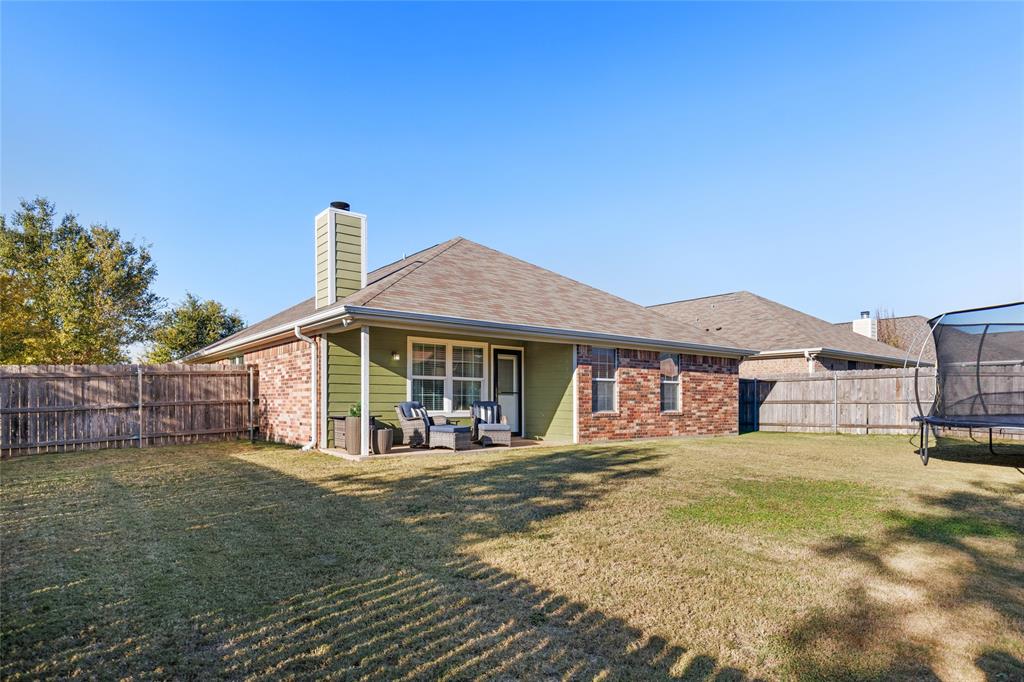 2565 Paddock Lane Robinson, TX 76706 - Photo 29 of 32 Rear view of house featuring a trampoline, a patio area, brick siding, a chimney, and a fenced backyard
