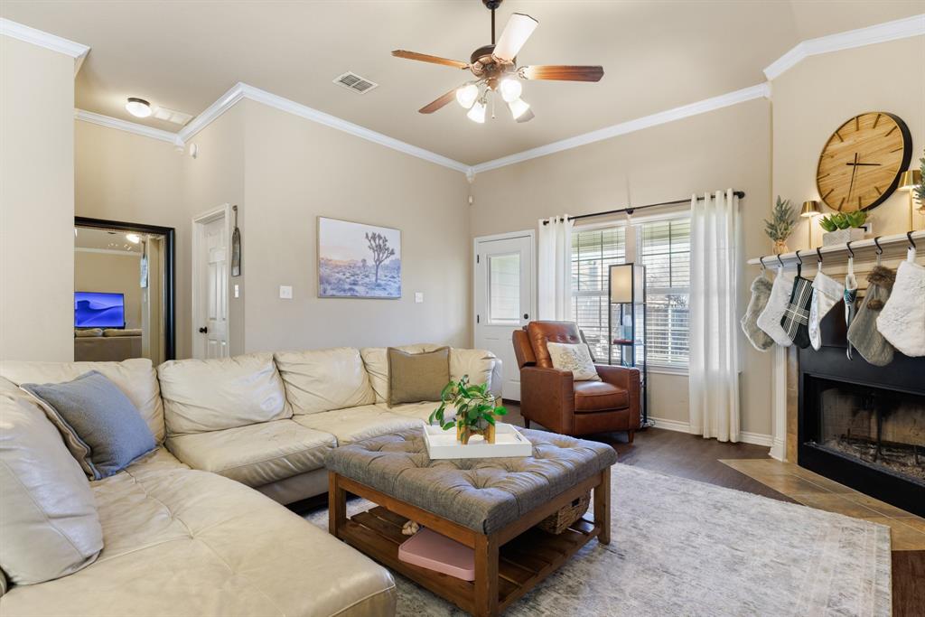 2565 Paddock Lane Robinson, TX 76706 - Photo 5 of 32 Living area featuring ornamental molding, wood finished floors, ceiling fan, and a fireplace with flush hearth