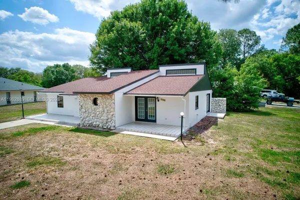 a view of a house with a yard and large tree