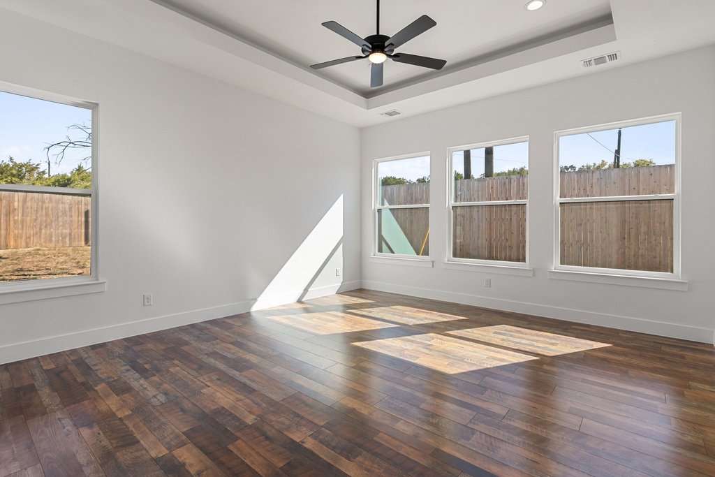 47 Peace Pipe Wimberley, TX 78676 - Photo 11 of 28 Unfurnished room featuring dark wood-style floors, ceiling fan, and a tray ceiling